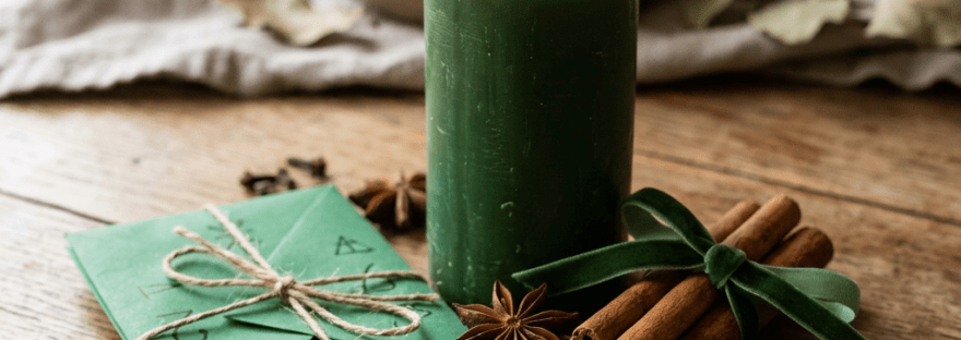 Green candle, handwritten notes, cinnamon sticks, star anise, and coin